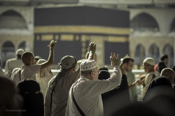 معتمرون محرمون يرفعون أيديهم بالدعاء أمام الكعبة المشرفة